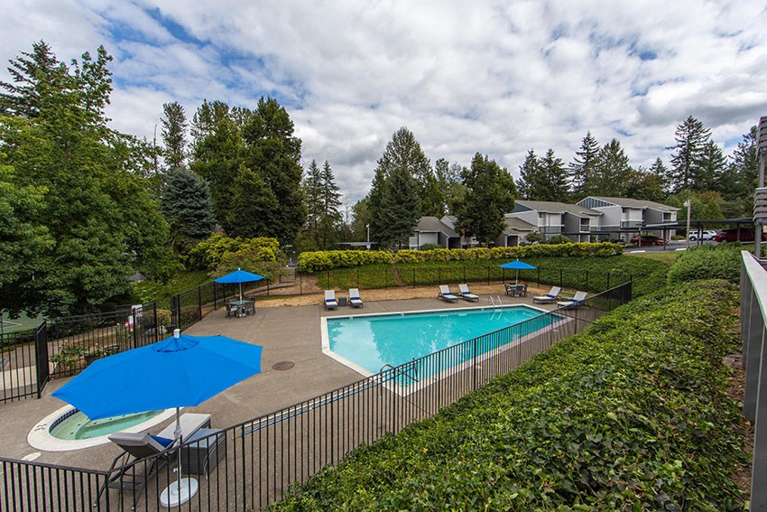 a swimming pool with tables and umbrellas next to a fence