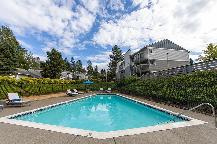 a swimming pool with chairs and a building in the background