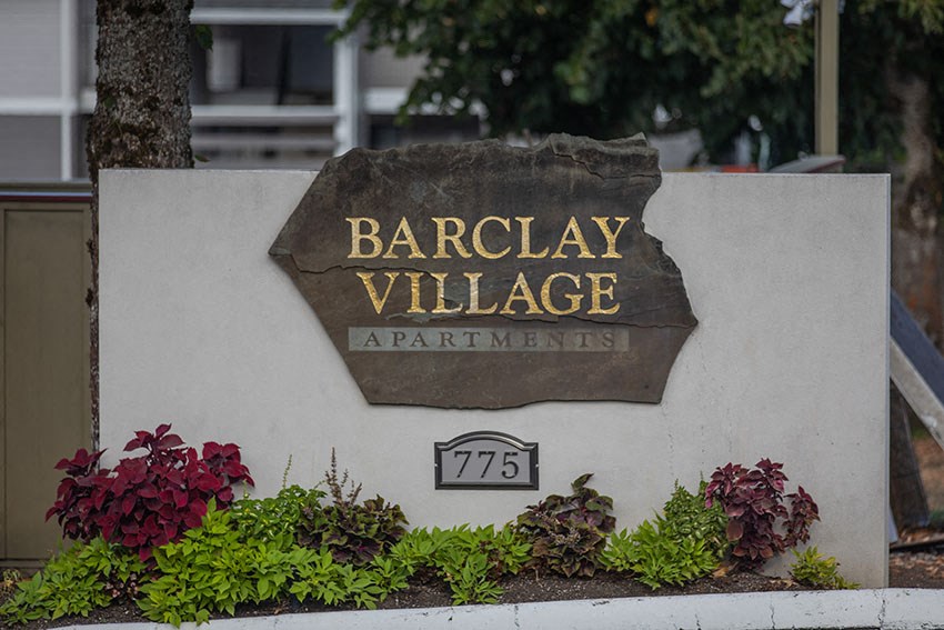a sign for barclay village apartments in front of a tree