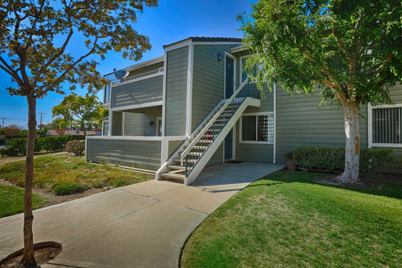 a gray house with stairs and a sidewalk in front of it