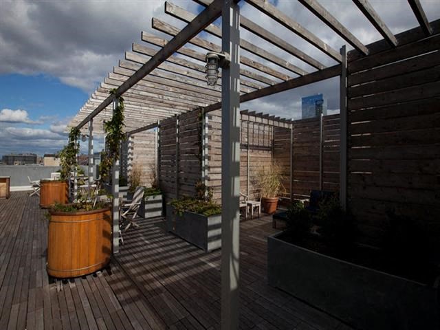 a roof terrace with a pergola and potted plants