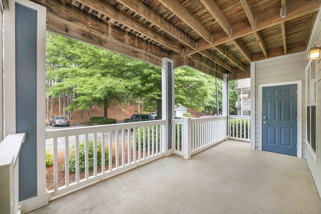 A porch with a white railing and a blue door.