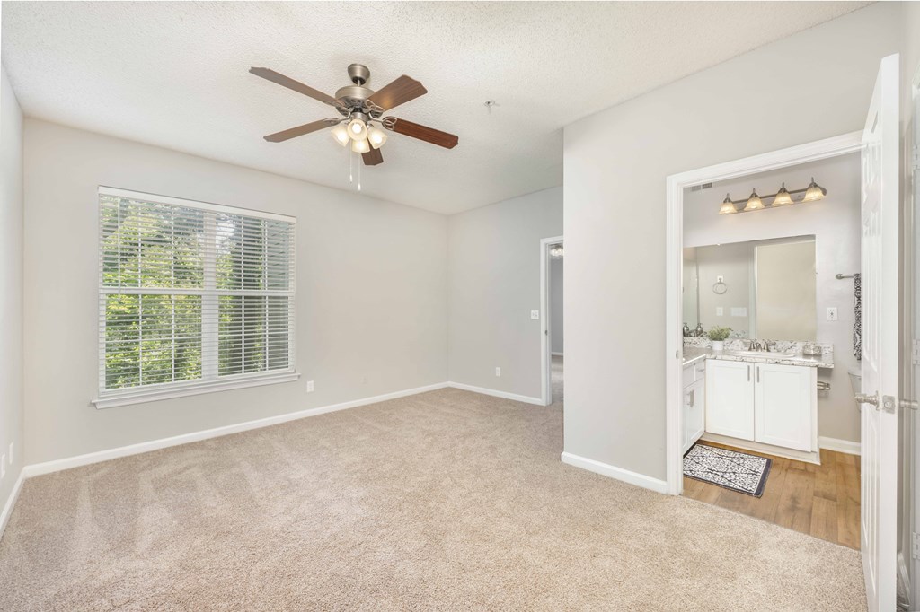 A spacious room with a ceiling fan and carpeted floor.