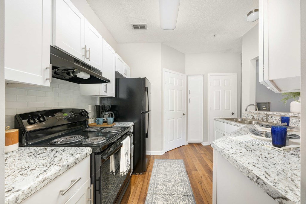 A kitchen with black appliances and white cabinets.