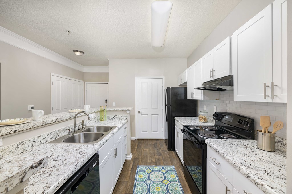 A kitchen with white cabinets and a black fridge.