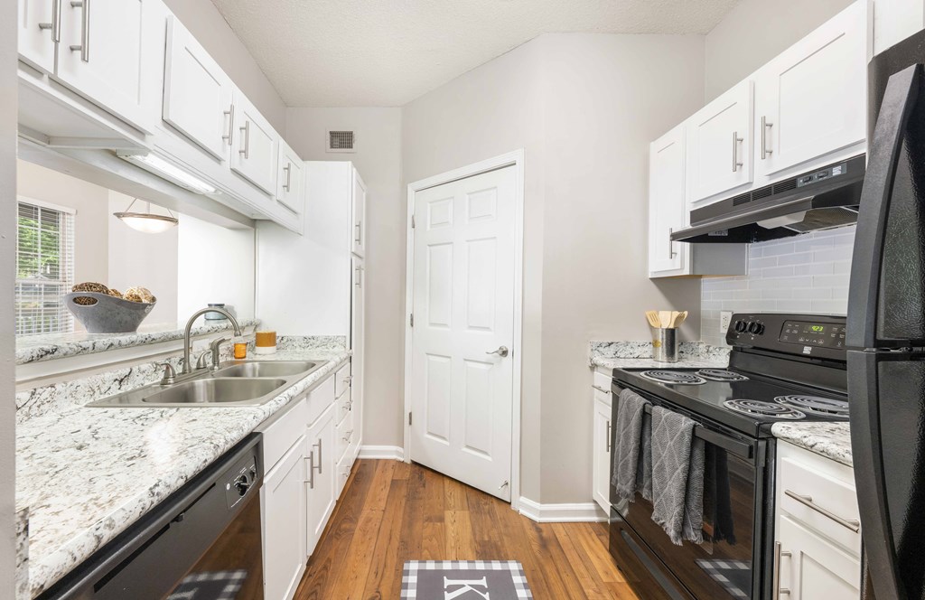 A kitchen with white cabinets and a black stove top oven.