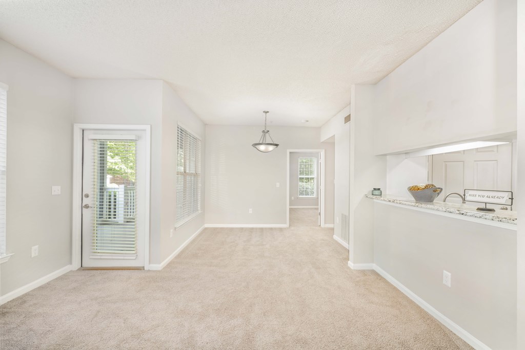 A spacious room with a carpeted floor and white walls.