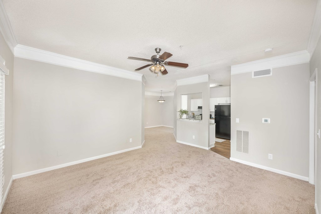 A spacious room with a ceiling fan and carpeted floor.