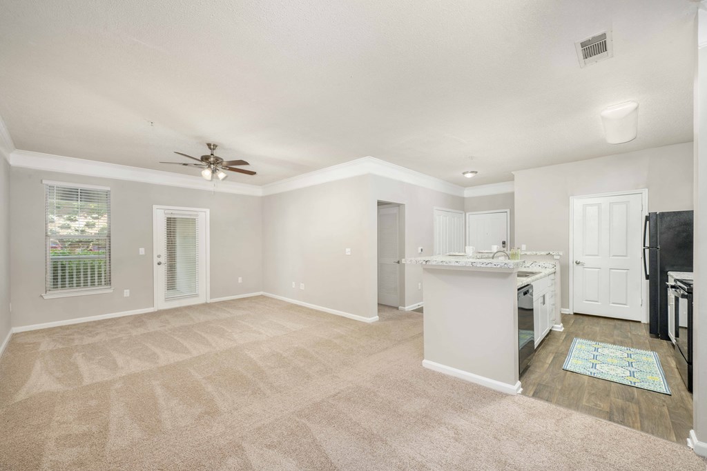 A spacious living room with a kitchen area in the background.