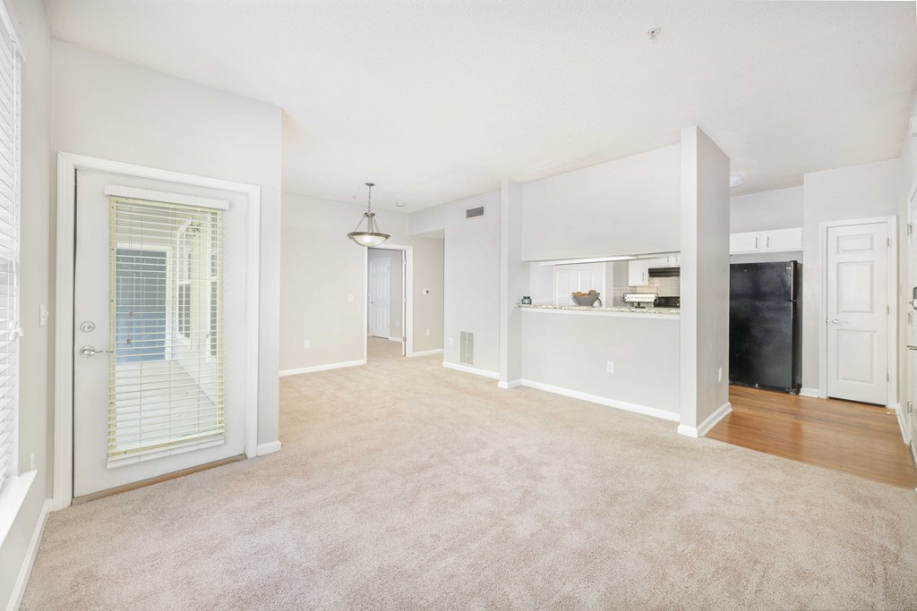 A spacious living room with a kitchen in the background.