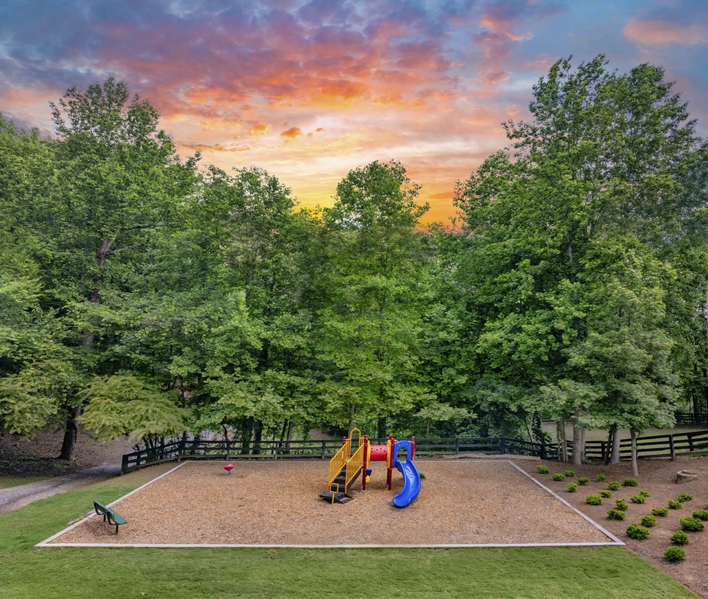 A playground with a slide and a green lawn.