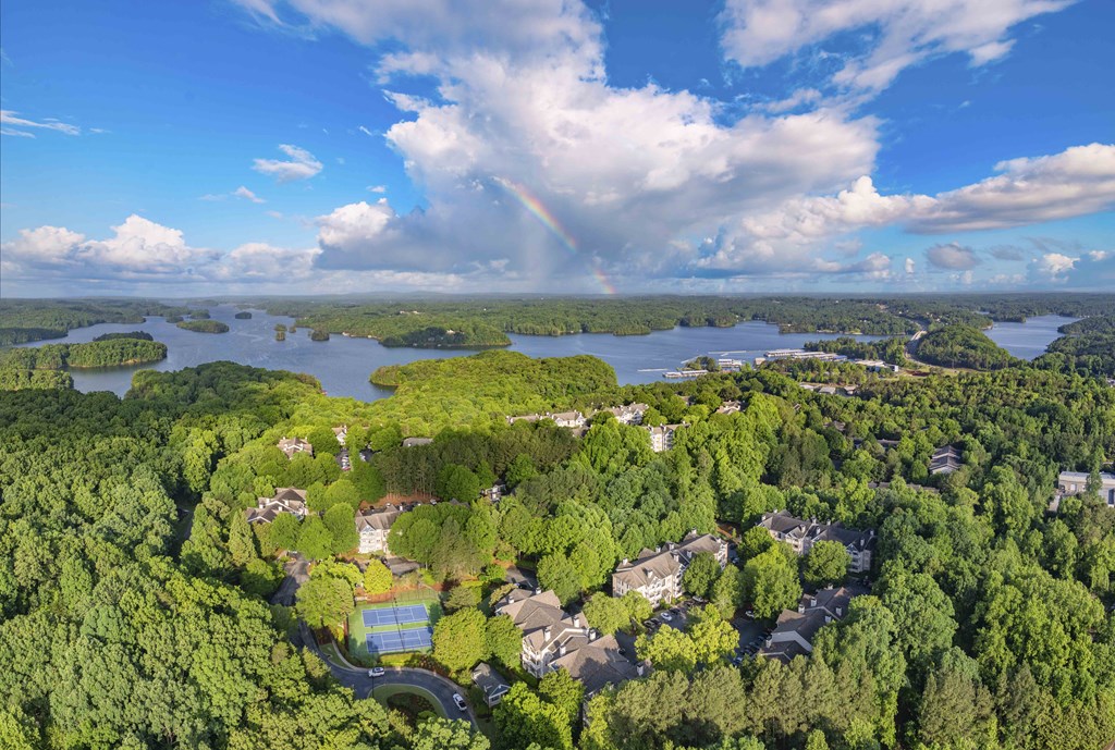 A rainbow appears over a residential area with a lake in the background.