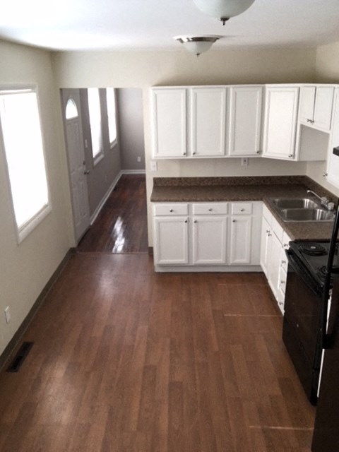 A kitchen with white cabinets and a black refrigerator.