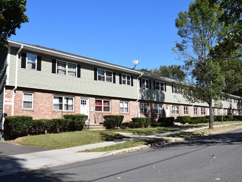 A long building with a red door and a green roof.