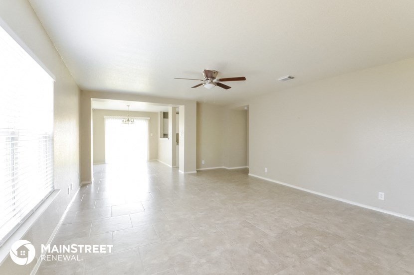 an empty living room with a ceiling fan