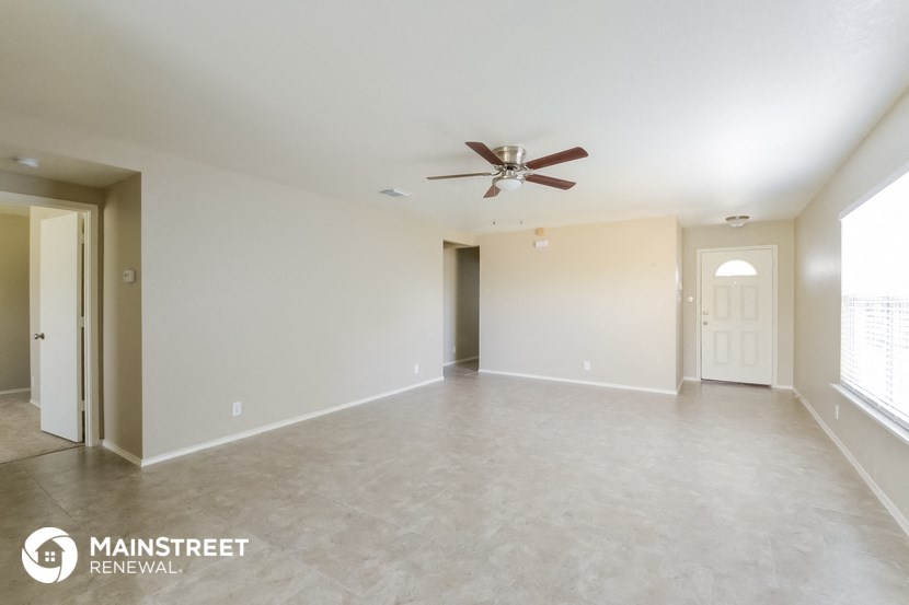 an empty living room with a ceiling fan