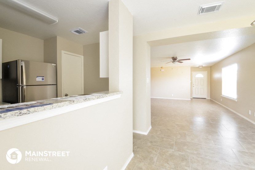 an empty kitchen and living room with a stainless steel refrigerator