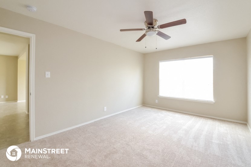 an empty living room with a ceiling fan and a window