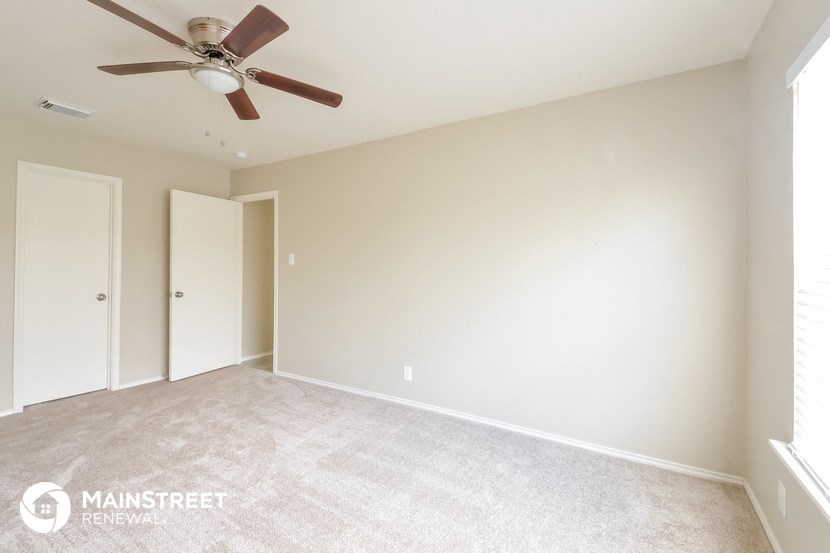 an empty room with a ceiling fan and white walls