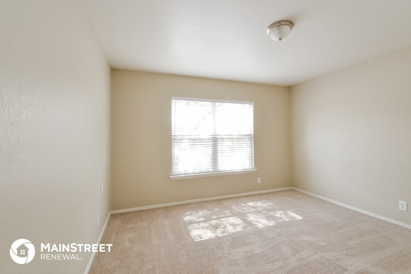 the spacious living room with a large window and beige carpeting