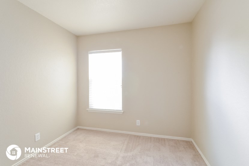 an empty room with a window and white walls