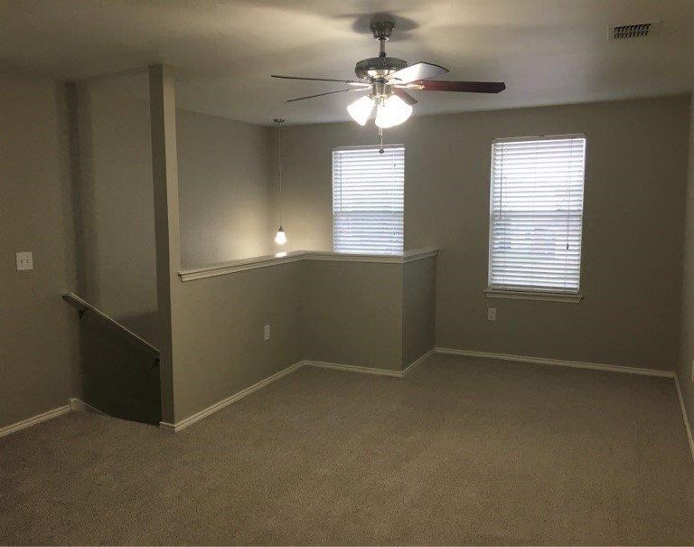 an empty room with a ceiling fan and two windows