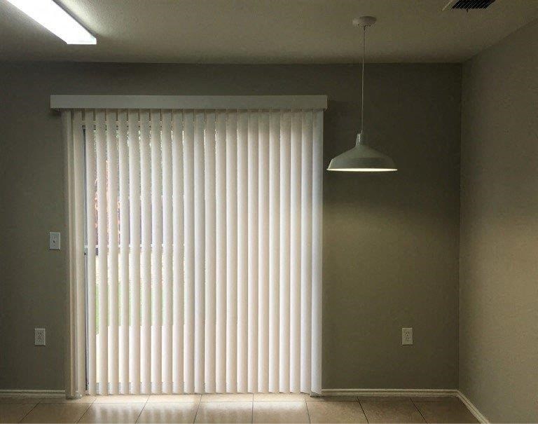 an empty living room with a large window with white blinds
