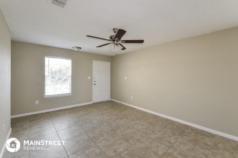 the spacious living room with ceiling fan and tiled floor