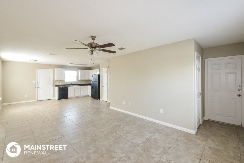 an empty living room with tile flooring and a ceiling fan