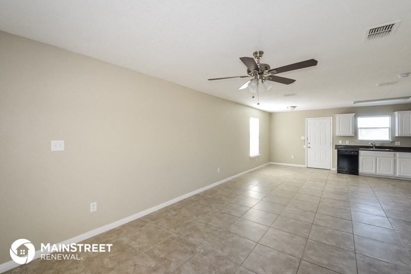 the spacious living room with tile flooring and a ceiling fan