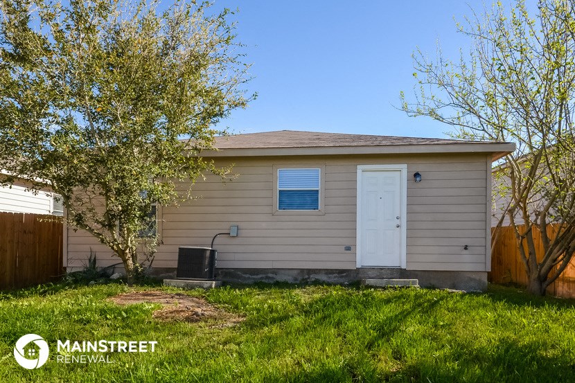 the exterior of a small tan house with a white door