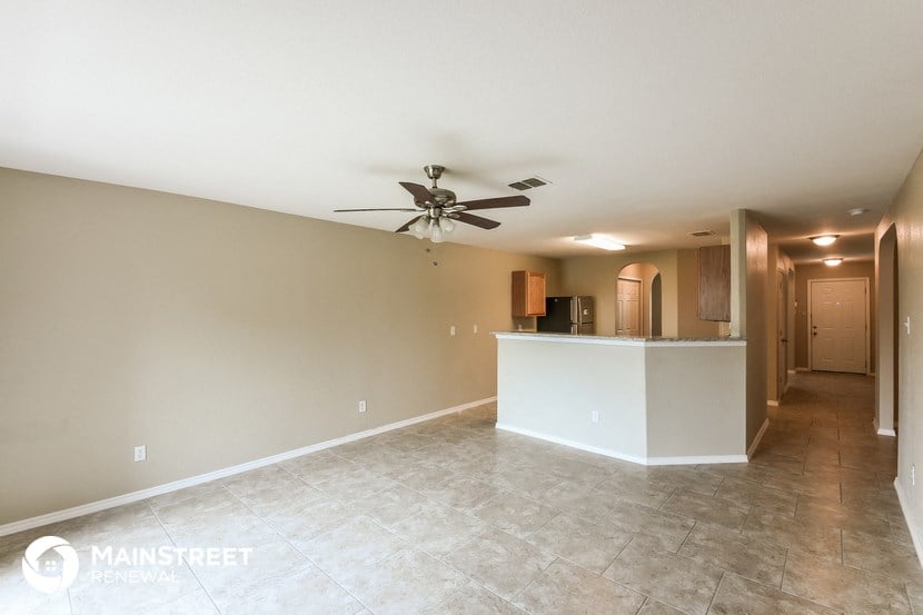 an empty living room and kitchen with a ceiling fan