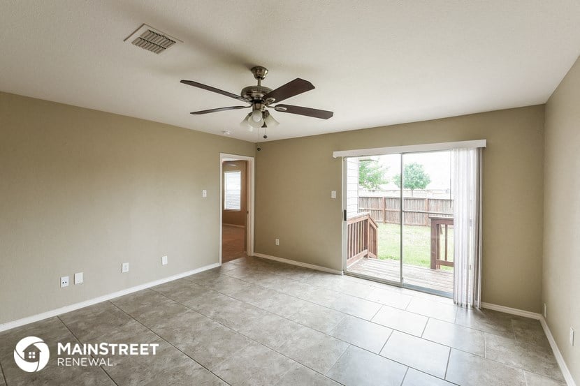 an empty living room with a ceiling fan and a sliding glass door