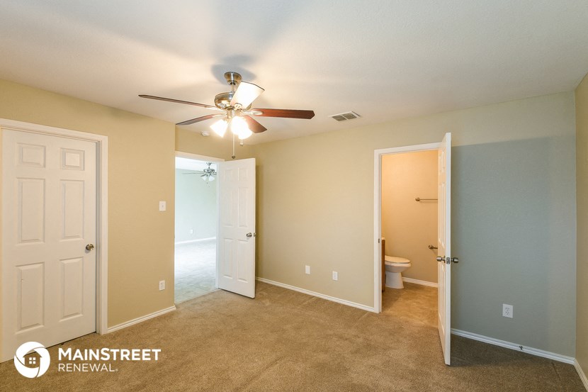 a bedroom with a ceiling fan and a door to a bathroom