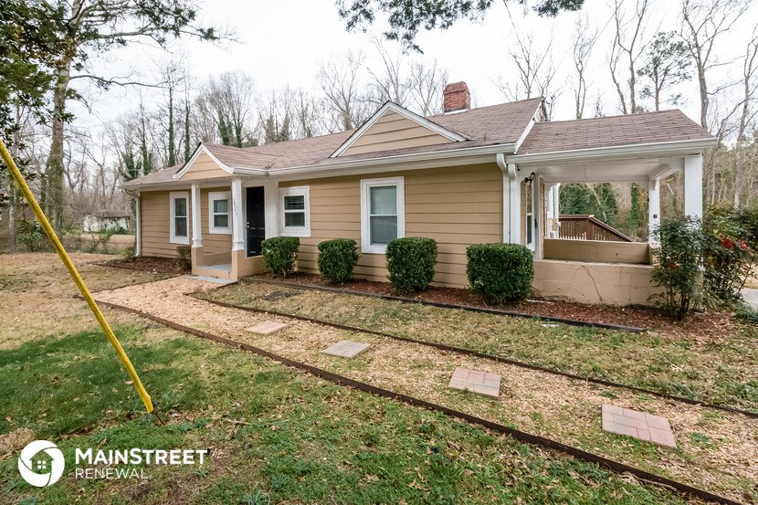 a small tan house with a yard and a porch