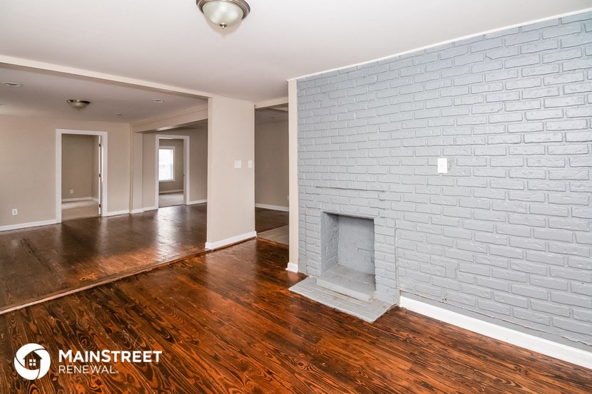 the living room and dining room of a house with wood floors and a brick fireplace