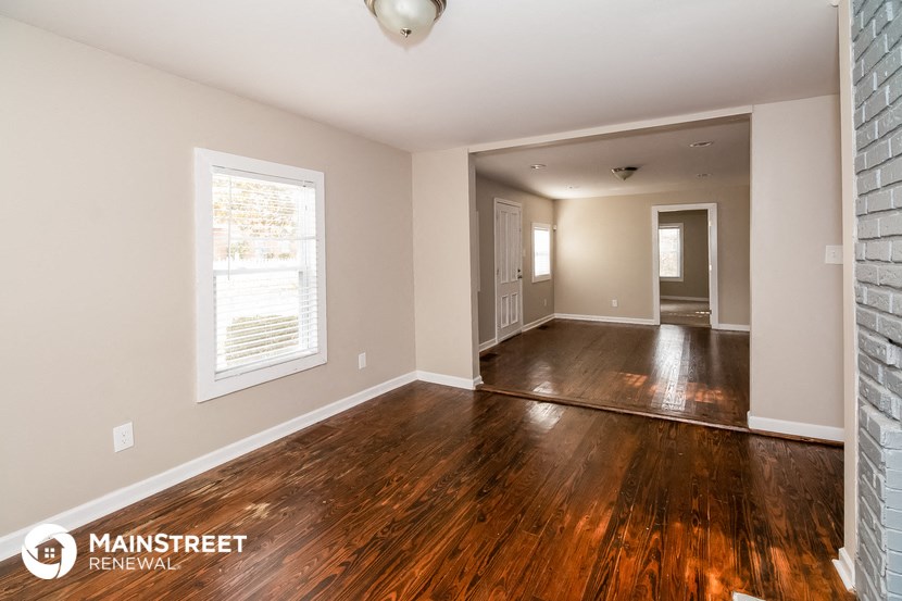 the living room and dining room of an empty house with wood floors and a window