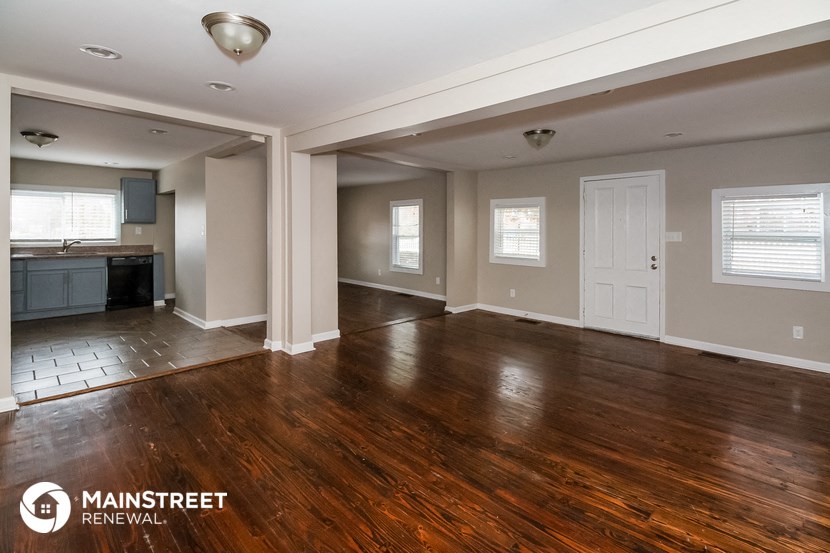 the kitchen and living room of a renovated house with wood flooring