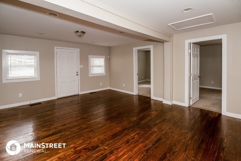 the living room of a home with wood floors and white walls