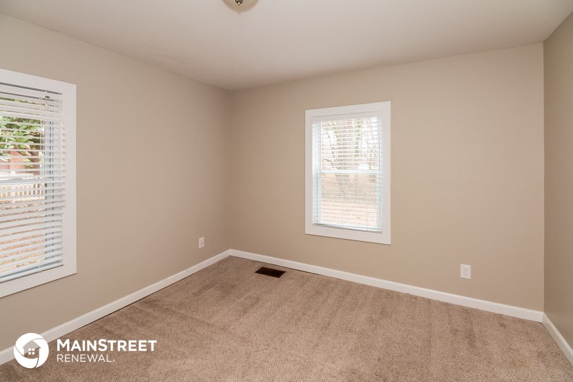 a empty room with a carpeted floor and two windows