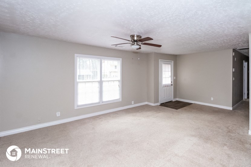 the living room of an empty house with a ceiling fan