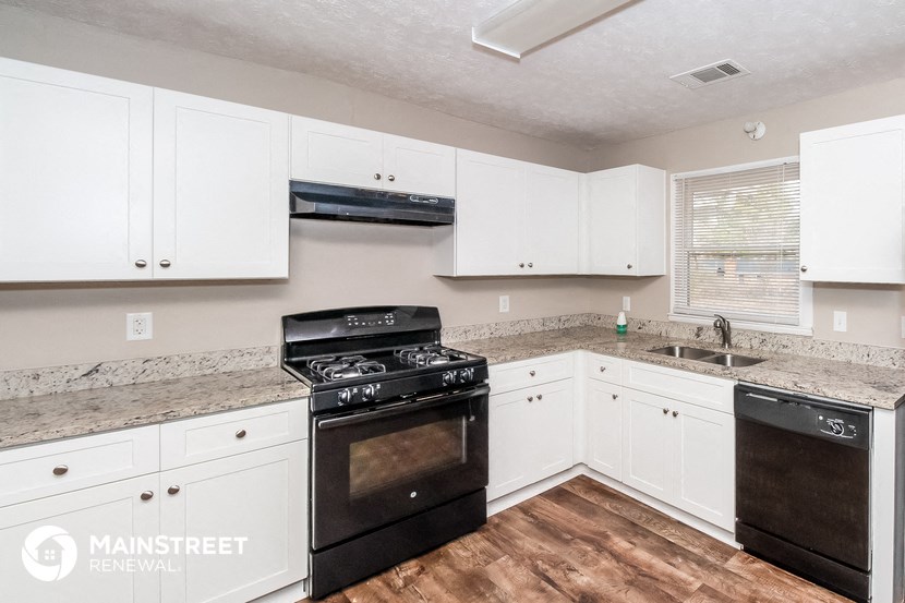 a kitchen with white cabinets and black appliances and a counter top