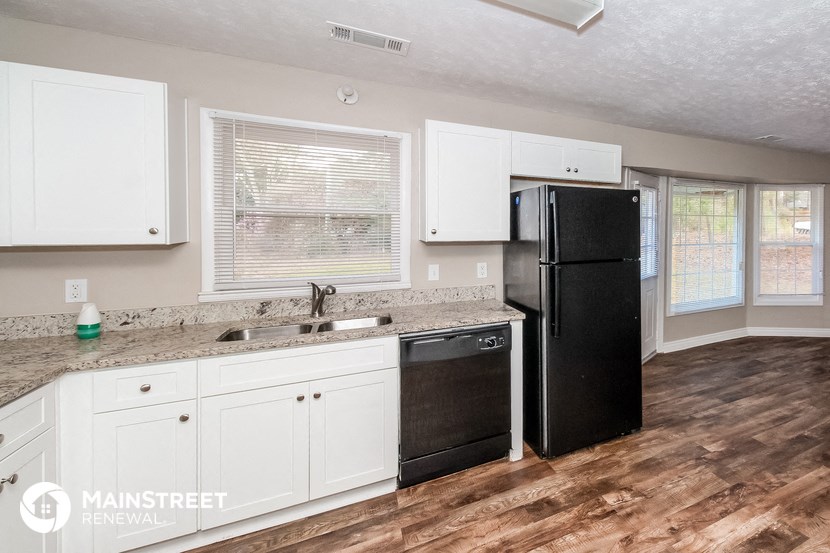 a kitchen with white cabinets and a black refrigerator