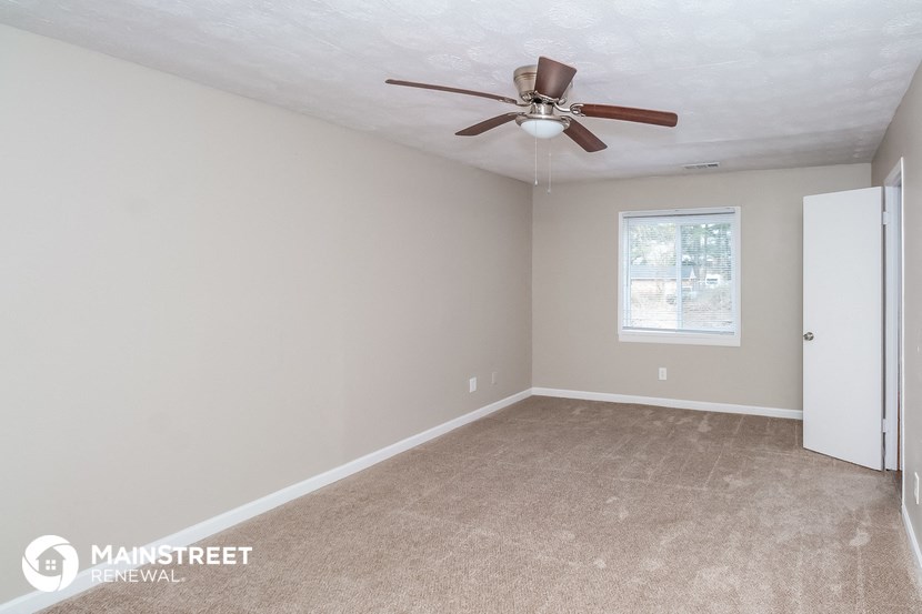 the bedroom of this home has a ceiling fan and beige carpet