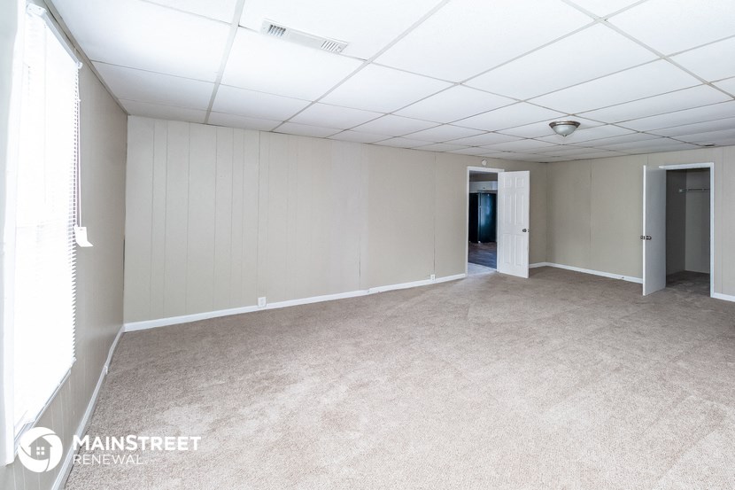 an empty room with a carpeted floor and a door to a hallway