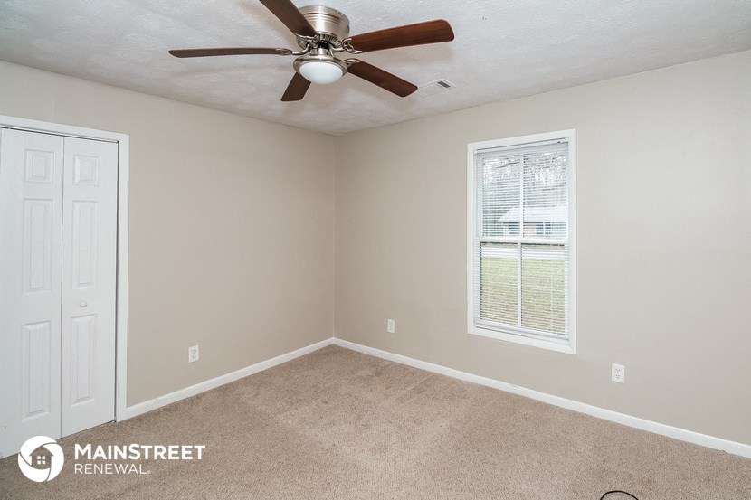 the bedroom of a rental home with a ceiling fan