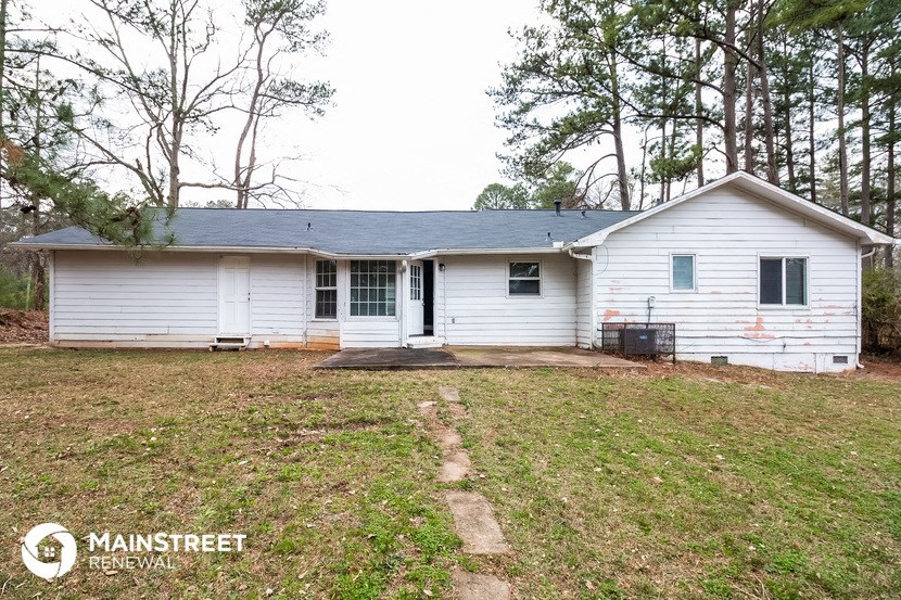 the front of a white house with a yard and some trees