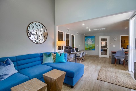 a living room with a blue couch and a table and chairs