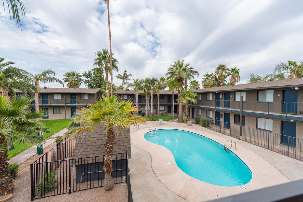 a resort style swimming pool in front of a building with palm trees