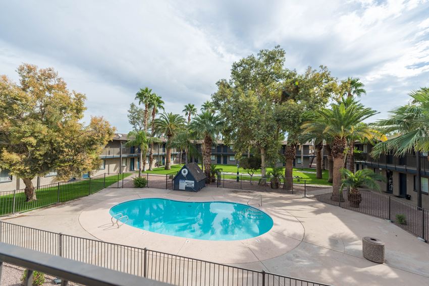 a swimming pool is surrounded by palm trees and a resort style building with condos